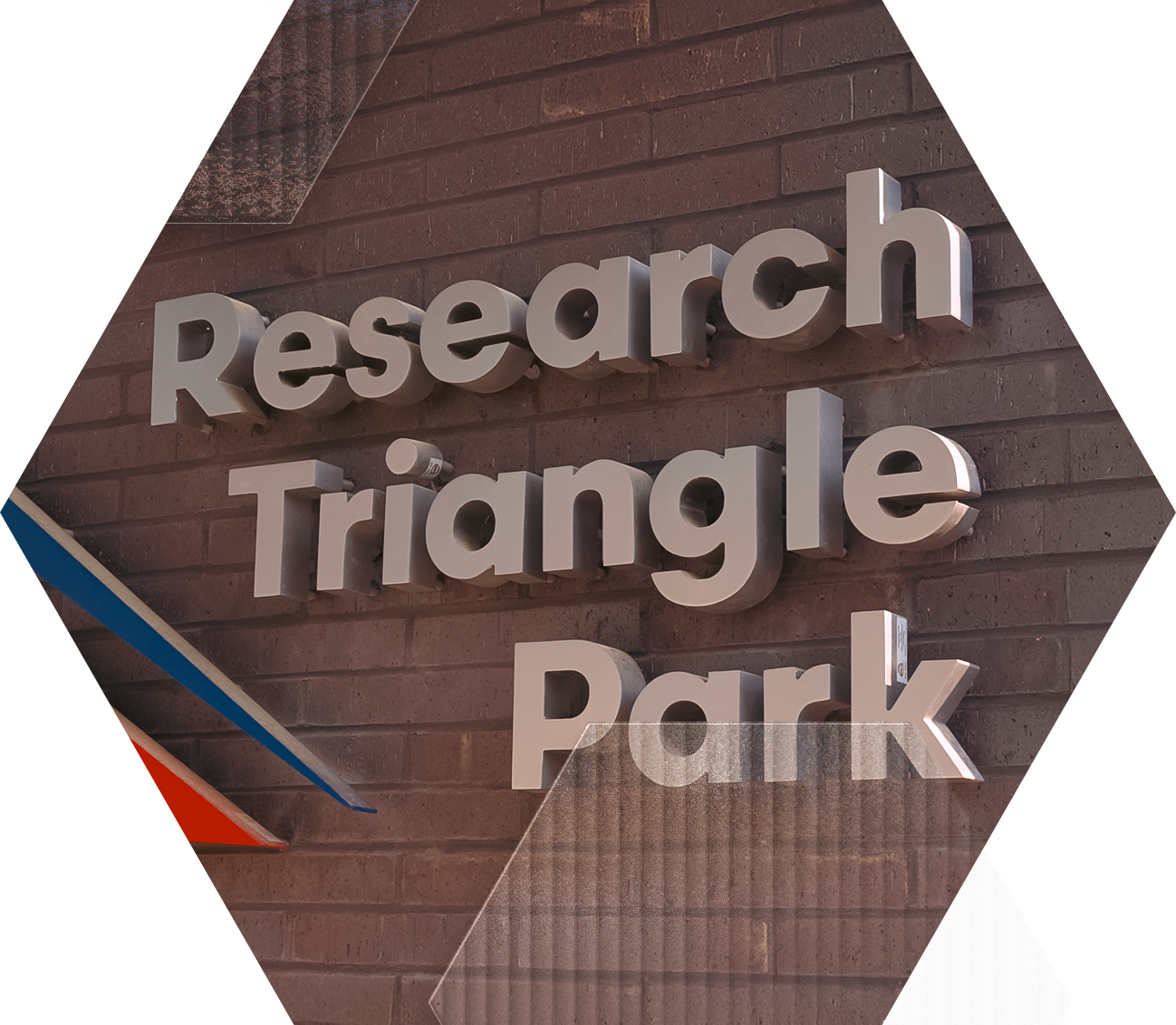 A wall sign with raised metallic letters reads “Research Triangle Park” against a background of brown bricks and geometric shapes in blue, red, and gray.