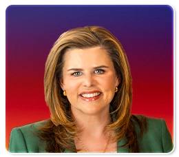 A woman with shoulder-length light brown hair, wearing a green blazer and gold jewelry, smiles against a gradient background of purple and red.